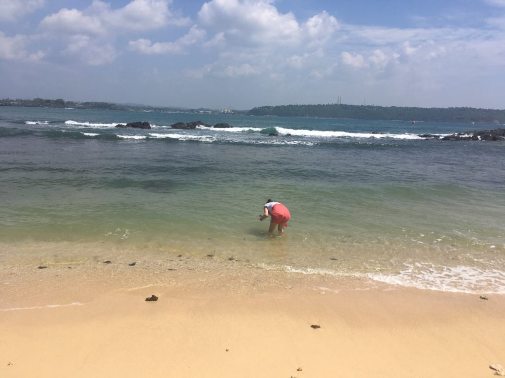 Sri Lankan sea & sand, with my coral coloured, sarong covered arse in the air, bending over to probably pick up a shell or touch the sea foam